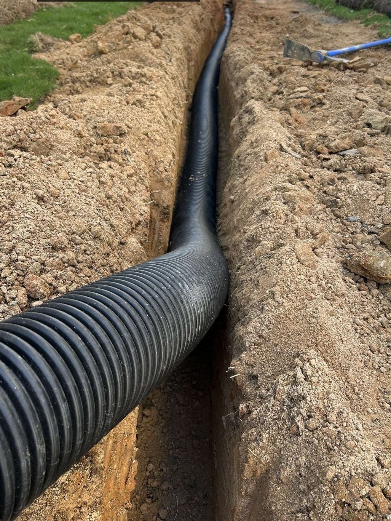 Black corrugated pipe in a trench; construction site.
