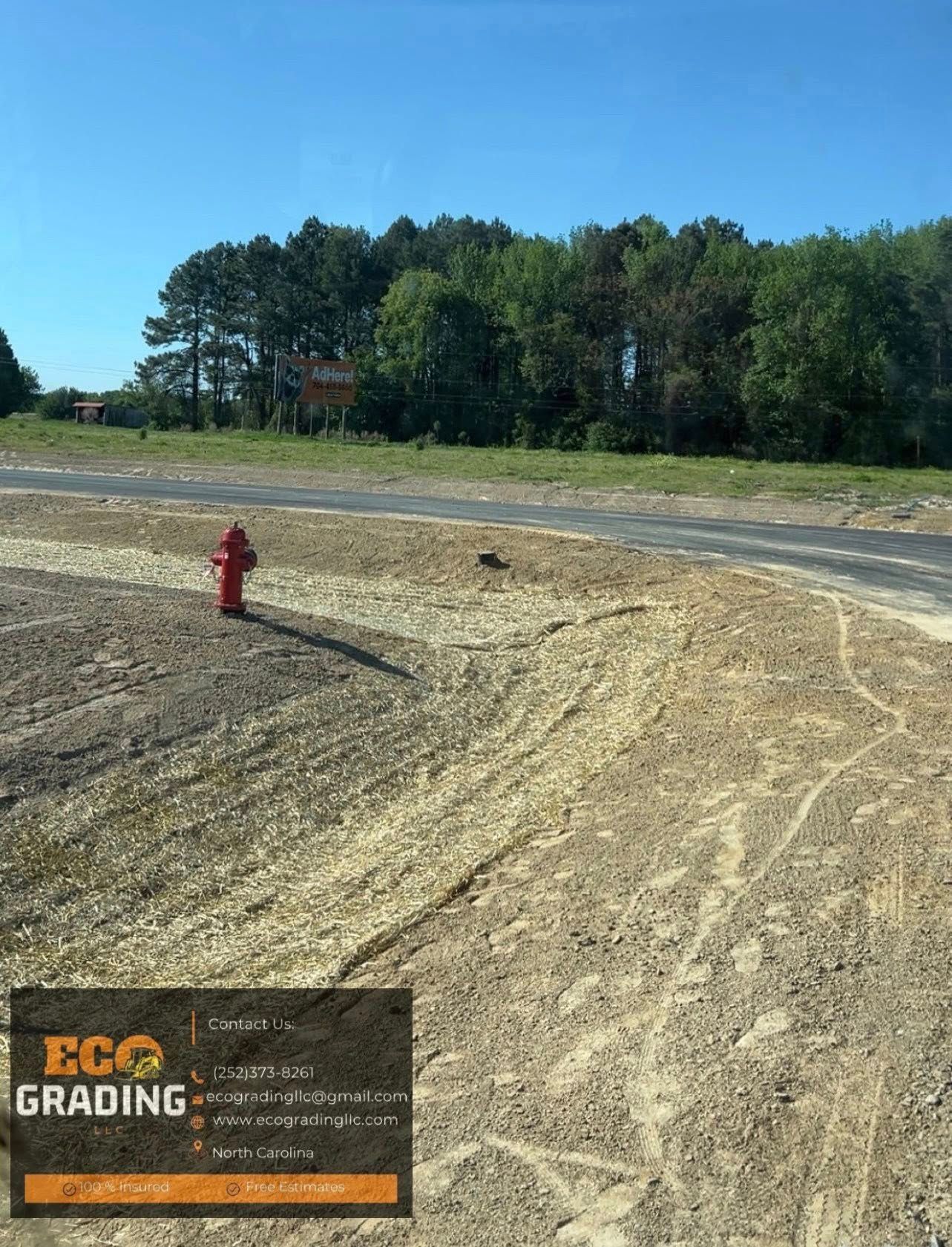Gravel lot with red fire hydrant, road, and trees under a blue sky.