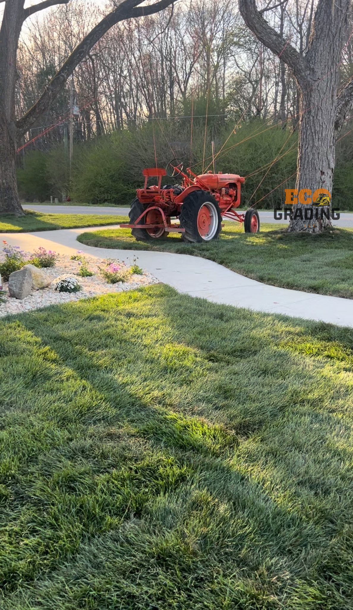 Orange tractor parked on a grassy lawn next to a path. A