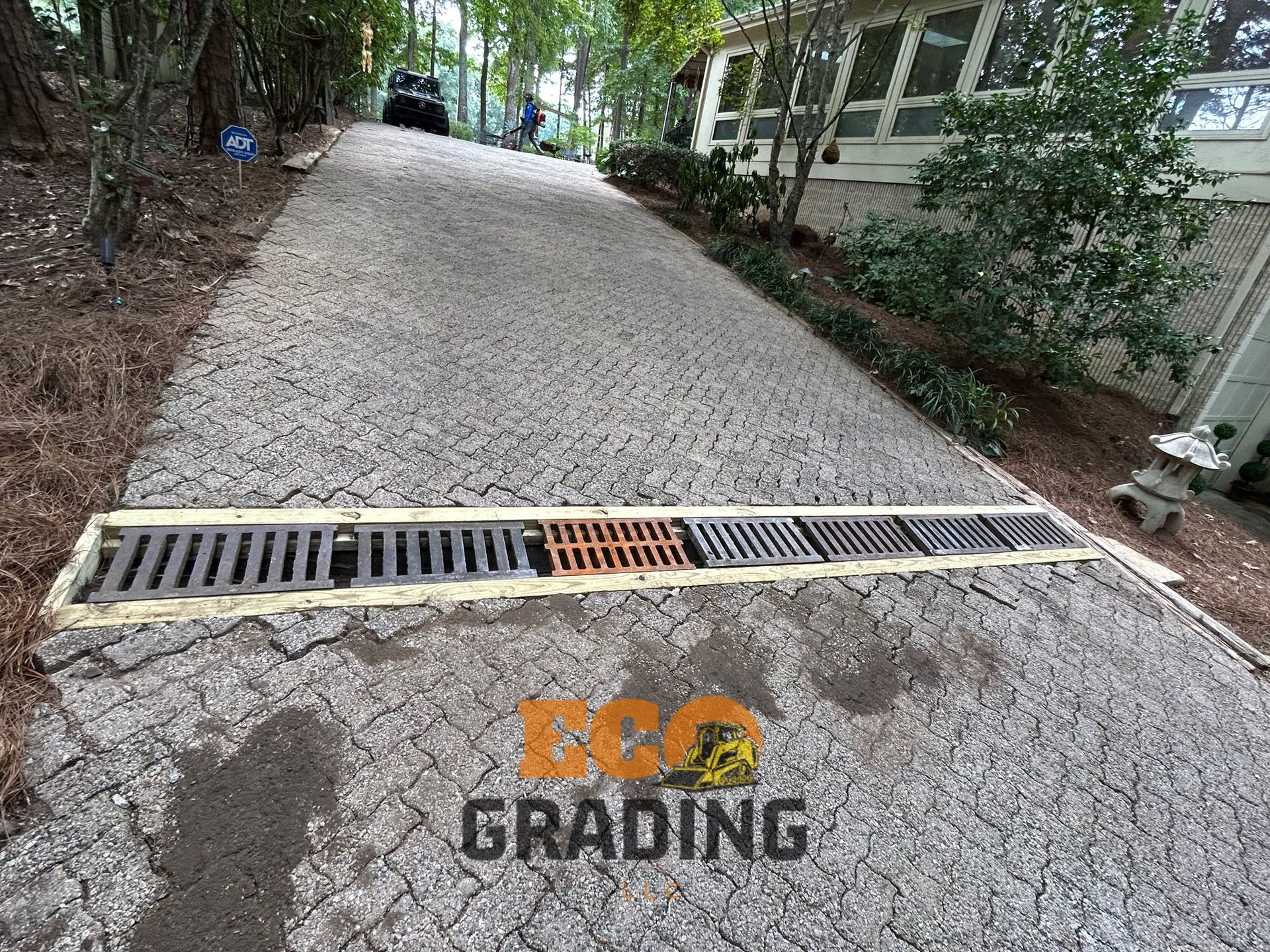 Driveway with gravel surface and drainage grate.