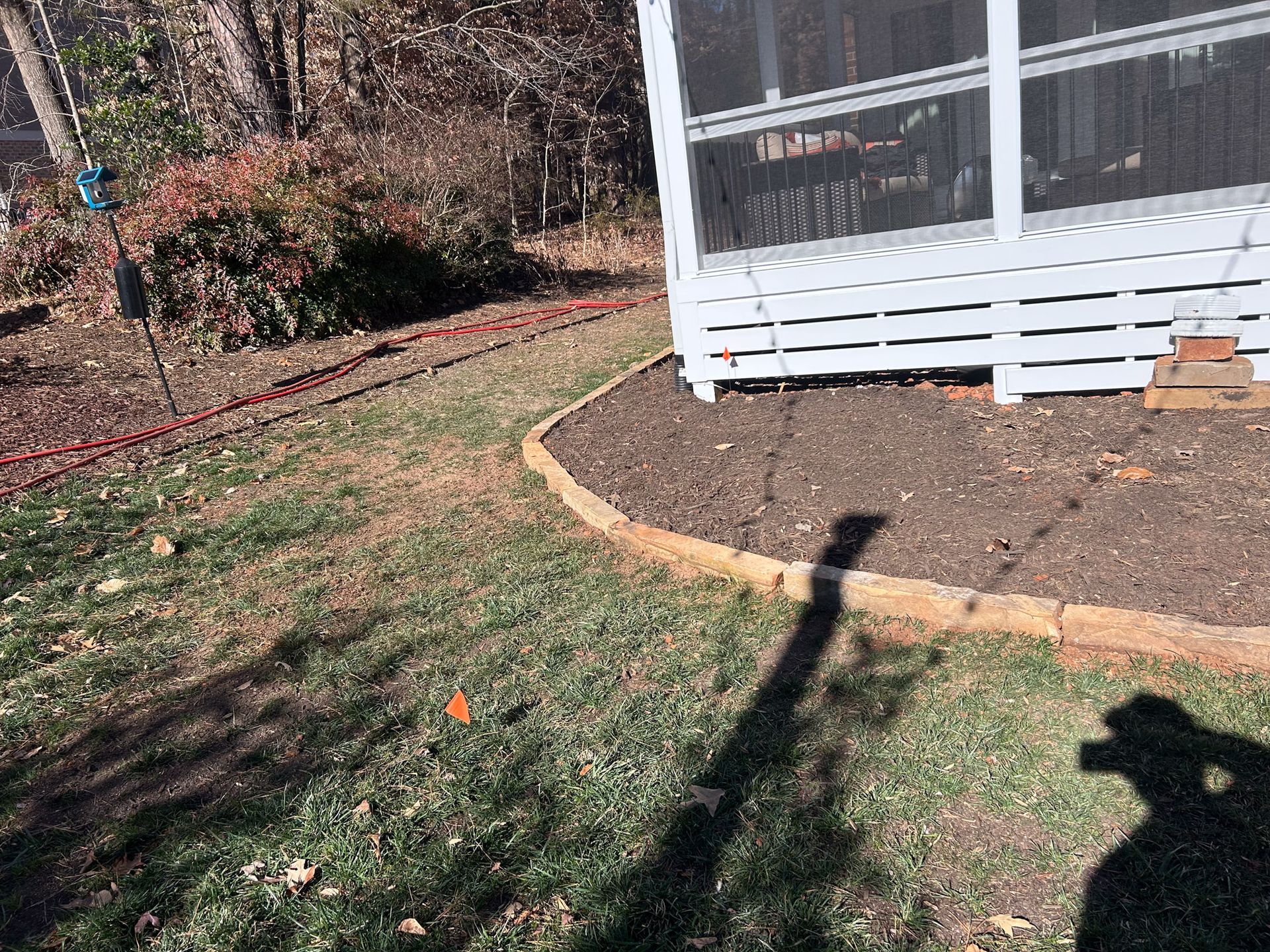 Yard with a screened porch, a brown mulch bed, and a lawn.