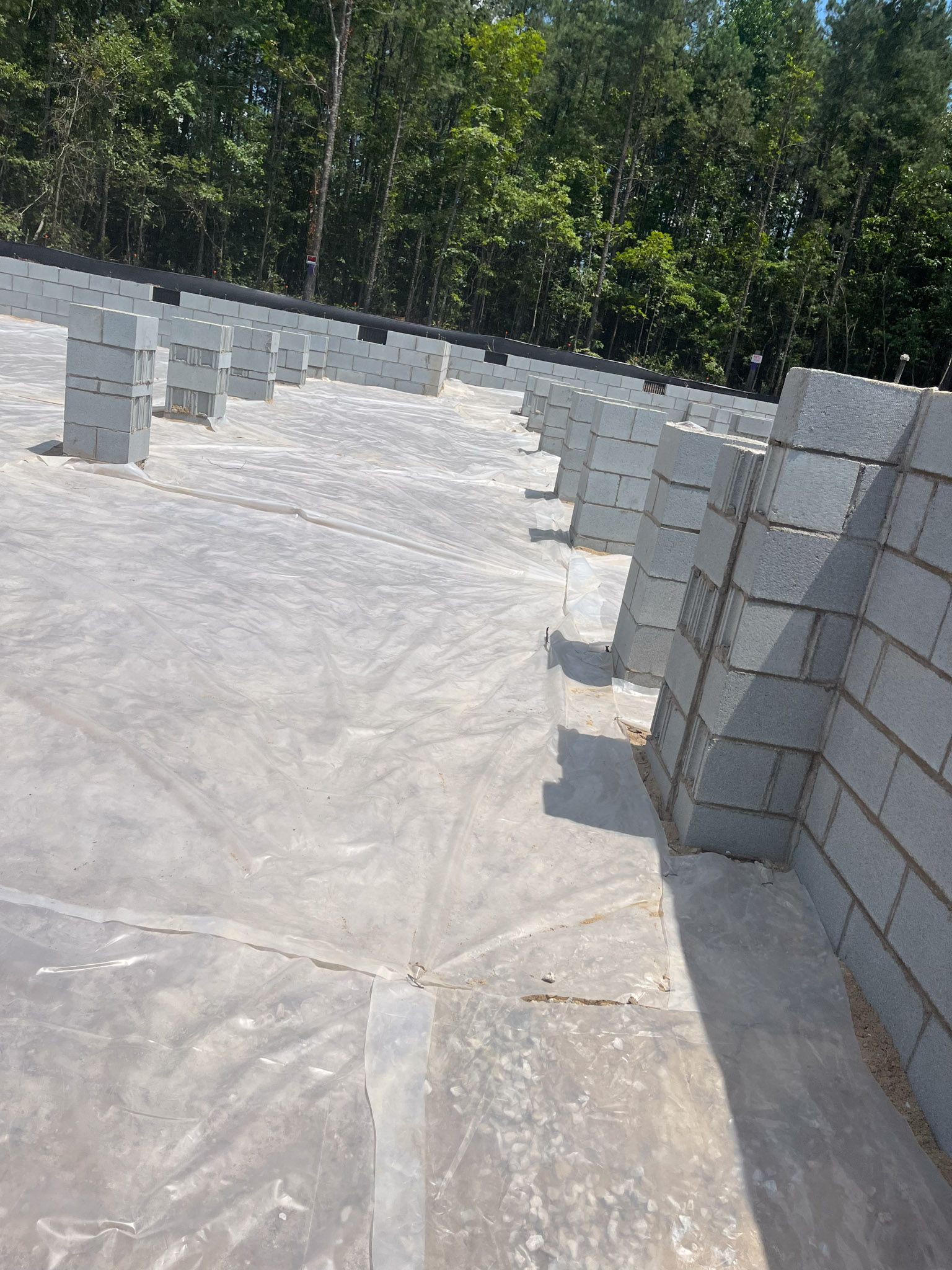 Concrete block columns on a flat, gray surface with trees in the background.