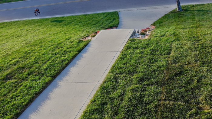 Concrete walkway with grassy slopes; person on a bicycle approaches in the distance.