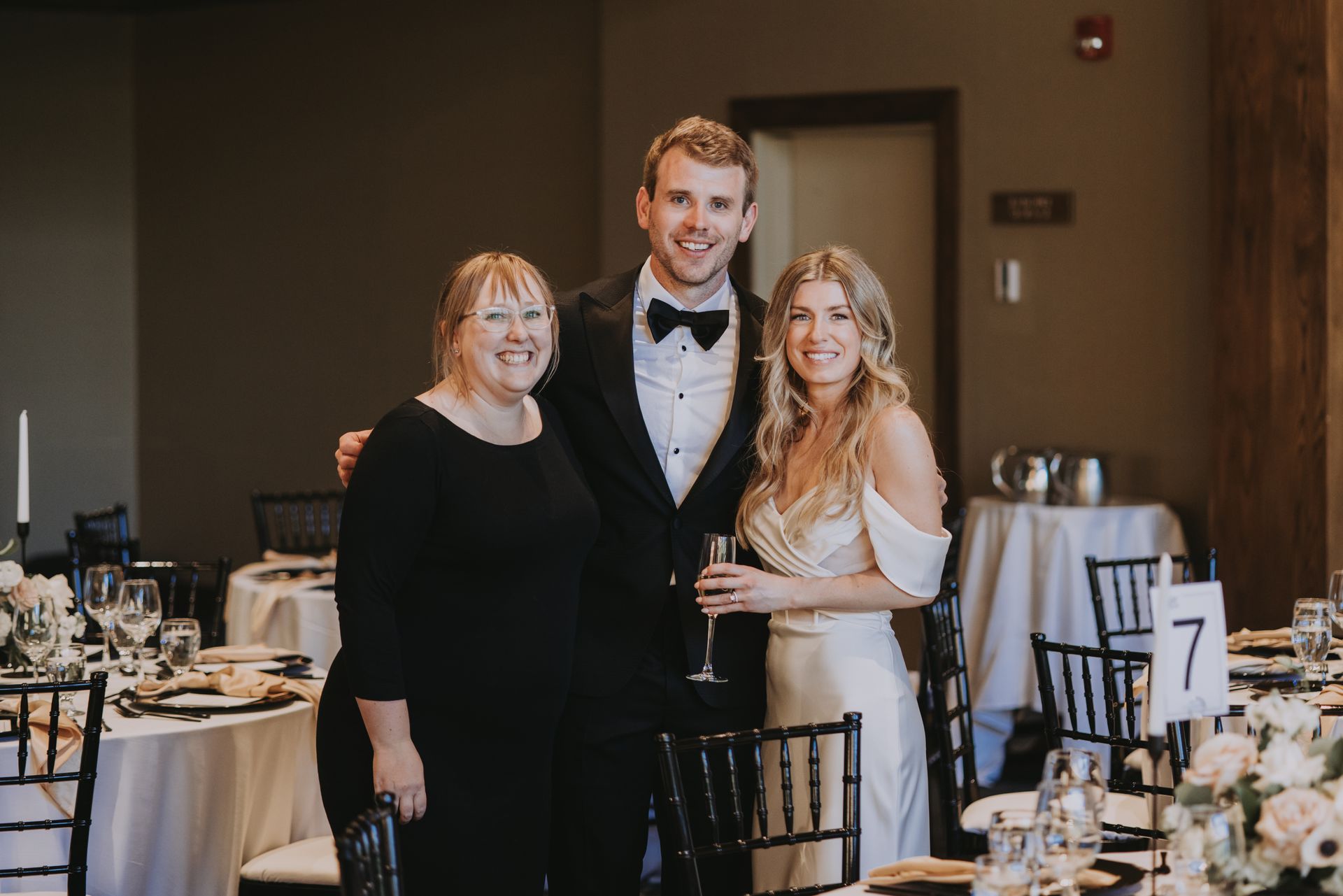 A bride and groom are posing for a picture with their mother at their wedding reception.