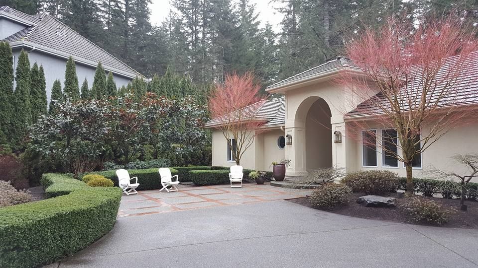 A large house with a large driveway and trees in the background