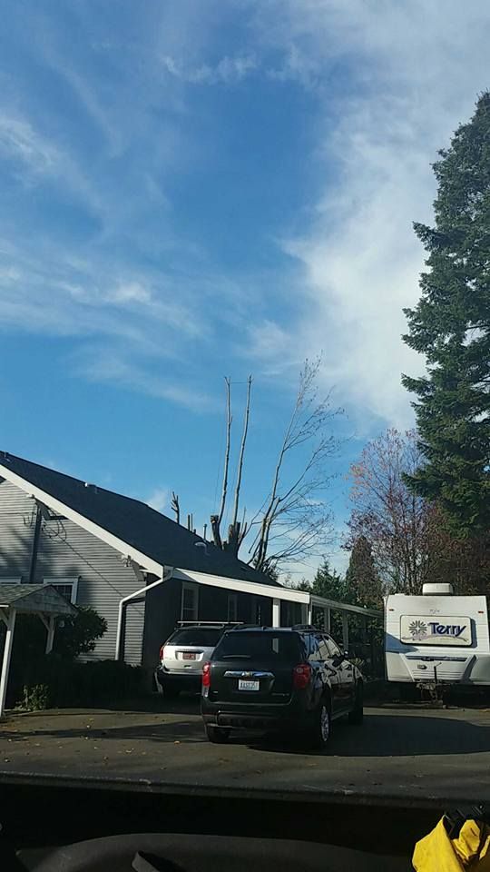 A car is parked in front of a house and a trailer.