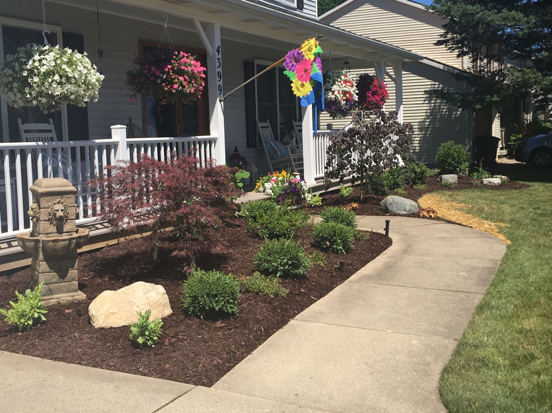 House exterior with flower beds, porch, hanging baskets, and a walkway.