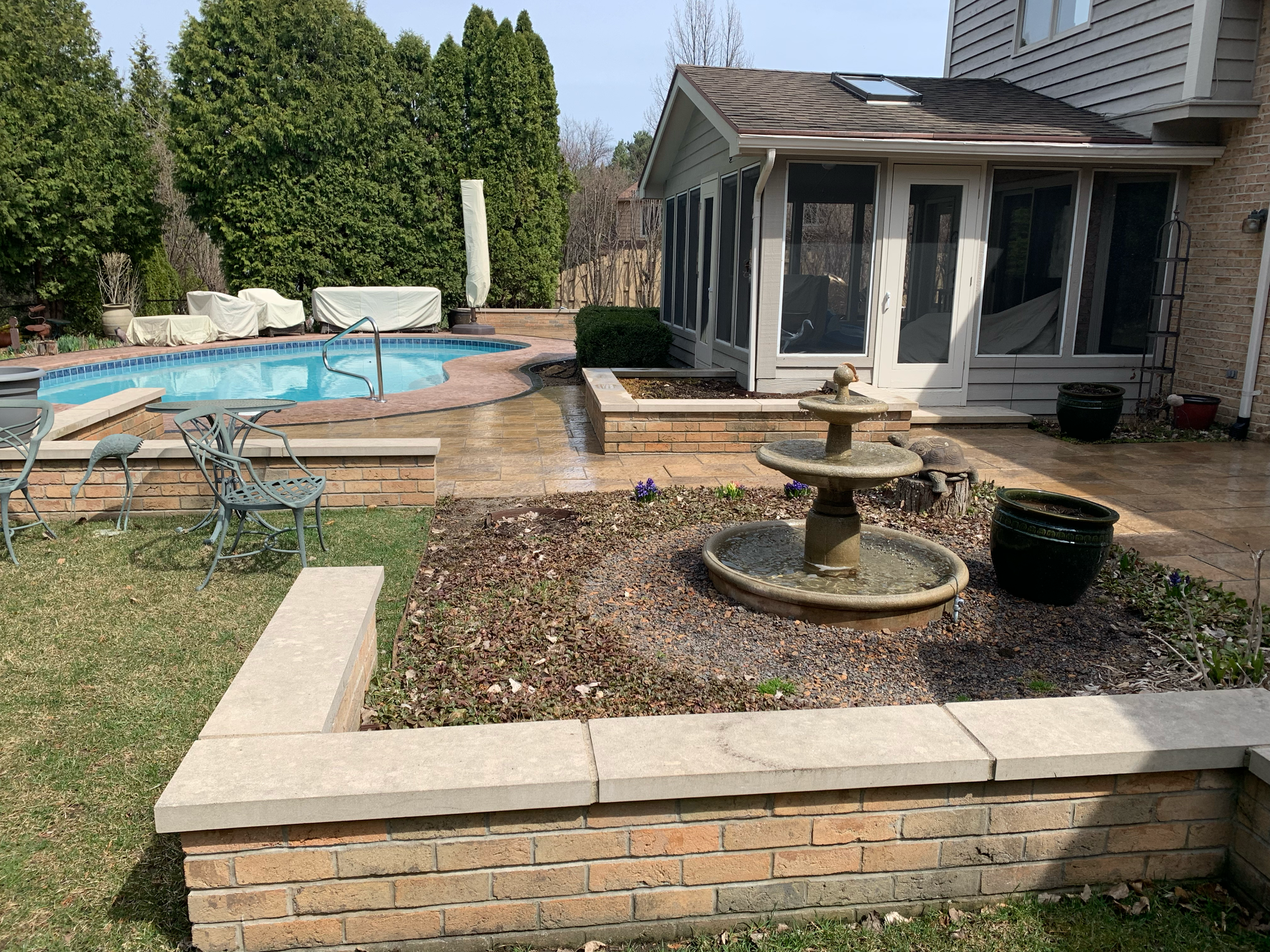 Backyard with pool, fountain, raised flower beds, and sunroom.