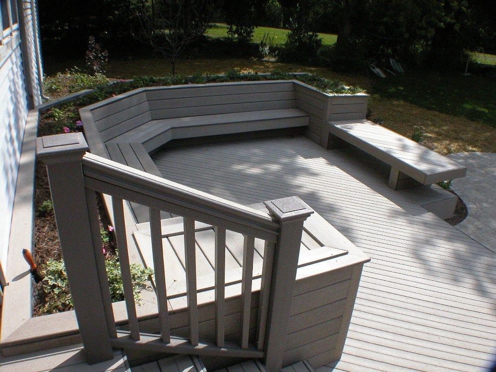 Composite deck with built-in seating area, beige railing and composite deck.