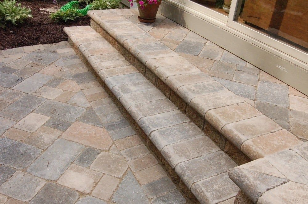 Stone steps leading up to a building with a patterned stone patio.