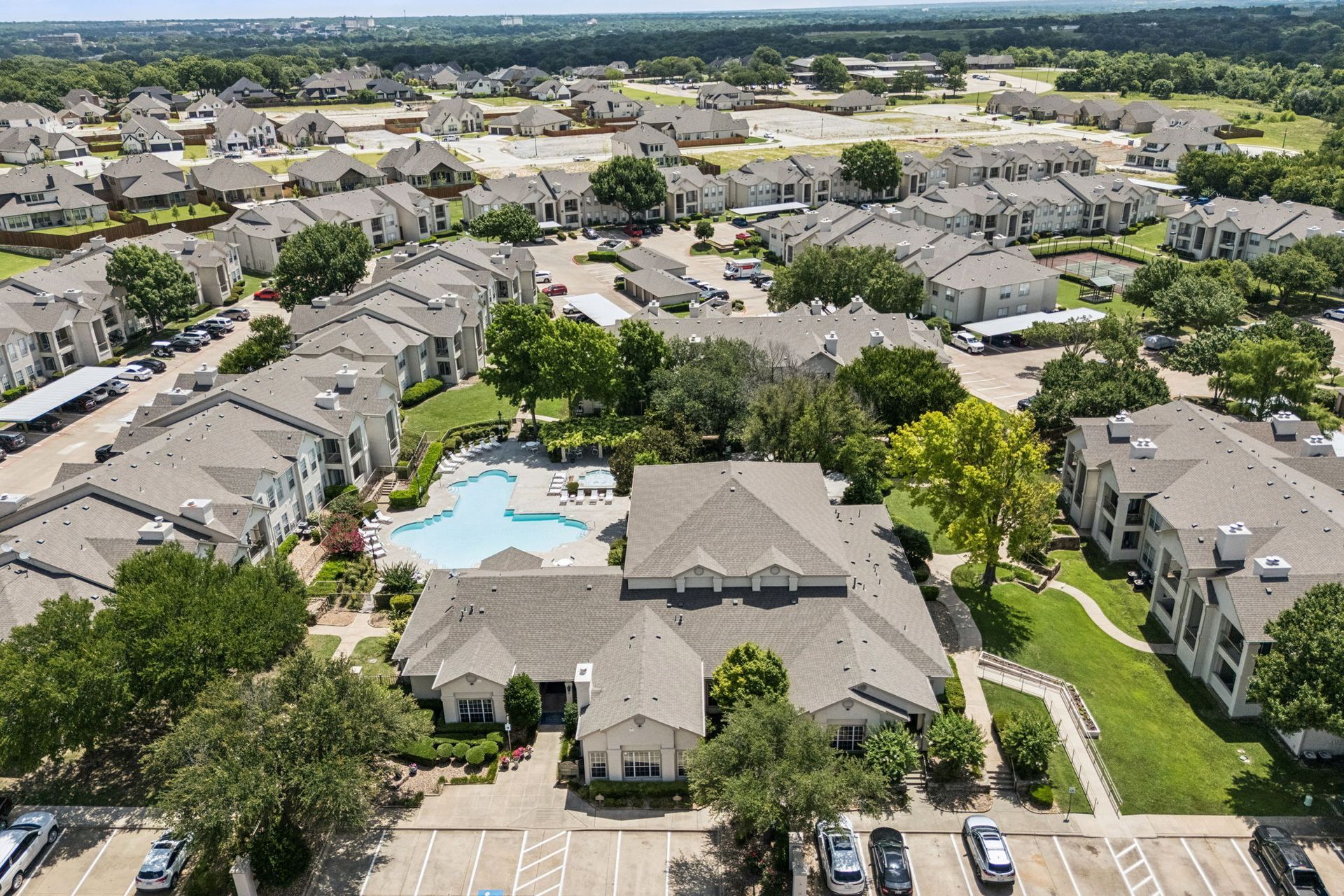 An aerial view of a large apartment complex with a pool in the middle.