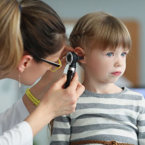 A little girl is getting her ears examined by a doctor.