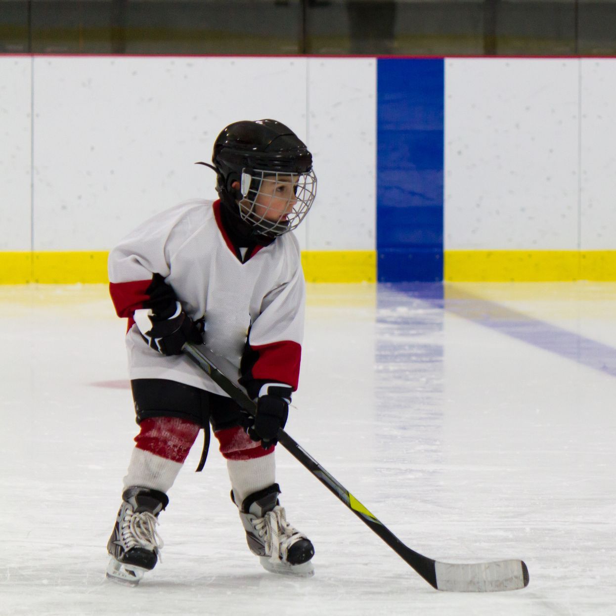 Young boy playing hockey on an ice rink.