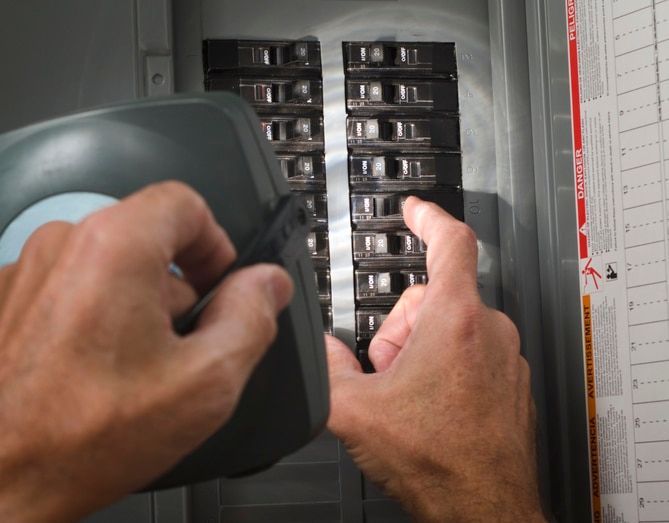 A person is working on an electrical panel with a light on it A person is working on an electrical panel with a light on it
