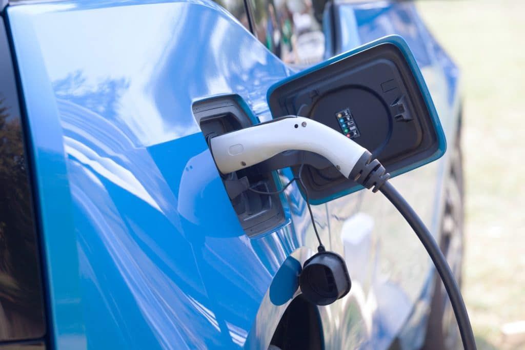 A blue electric car is being charged at a charging station.