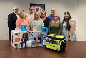 A group of people are posing for a picture in front of a table full of gifts.