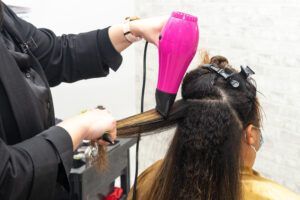 A woman is getting her hair blow dried by a hairdresser.