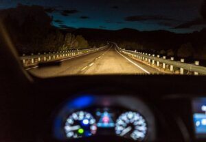 A car is driving down a highway at night.