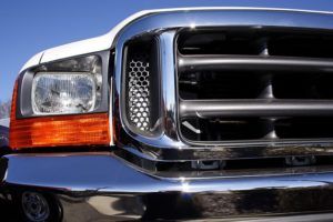 A close up of a truck 's headlight and grille.