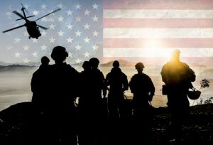 A group of soldiers are standing in front of an american flag and a helicopter.