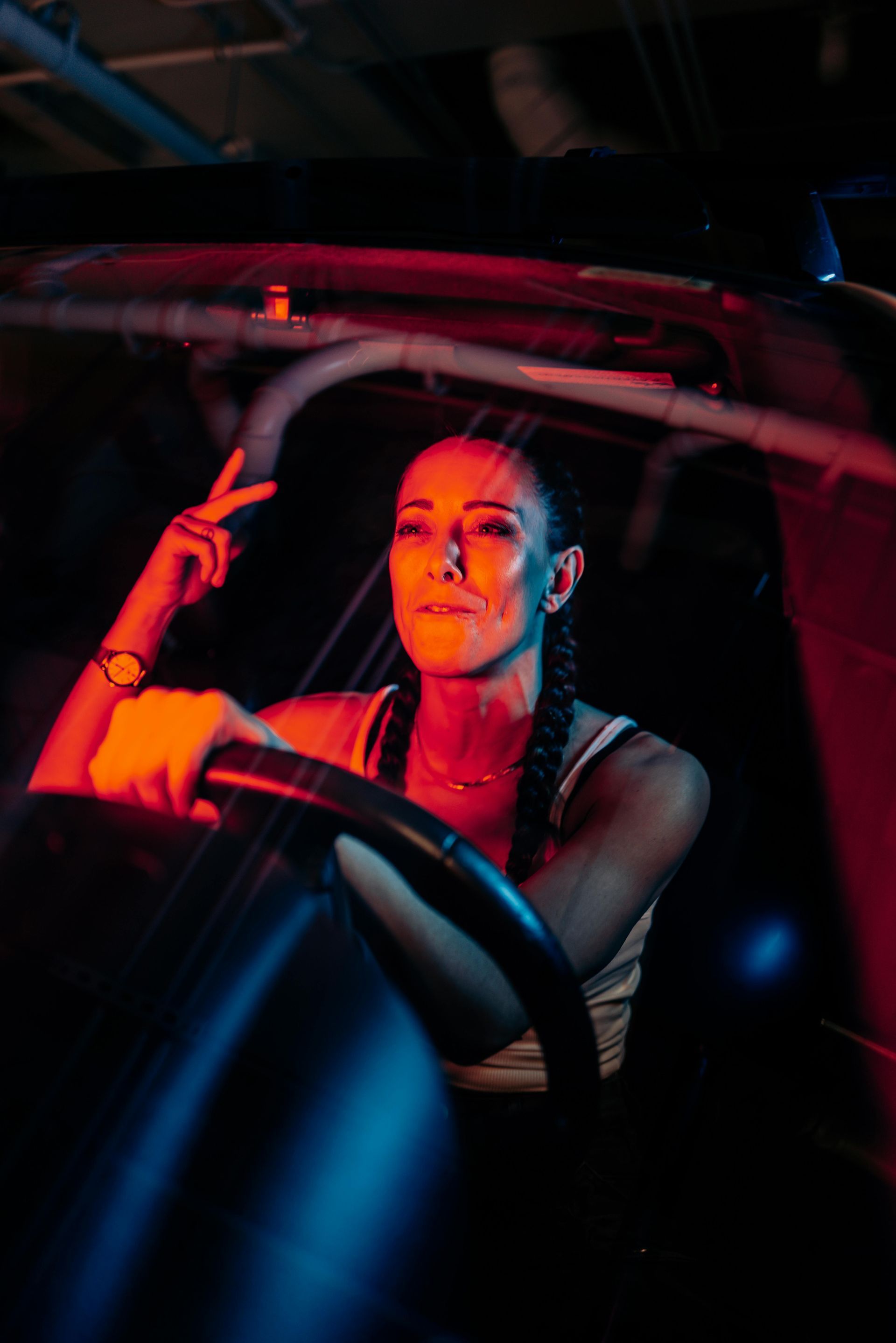 A woman is driving a car at night and giving a peace sign.