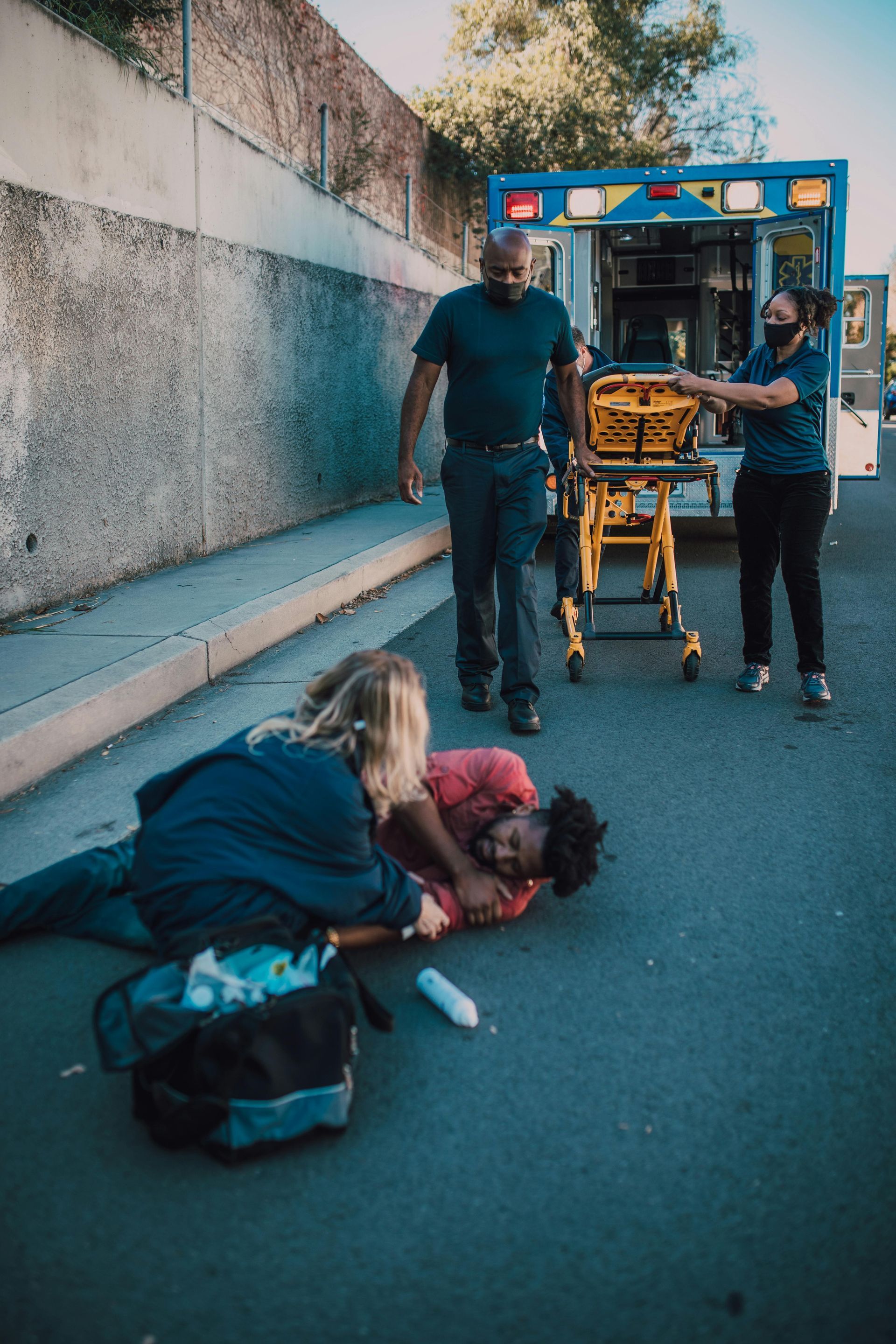A man is laying on the ground with an ambulance in the background.