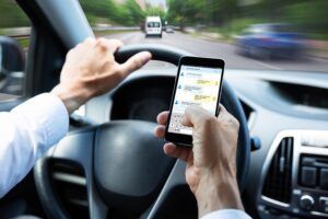 A man is driving a car and using a cell phone.