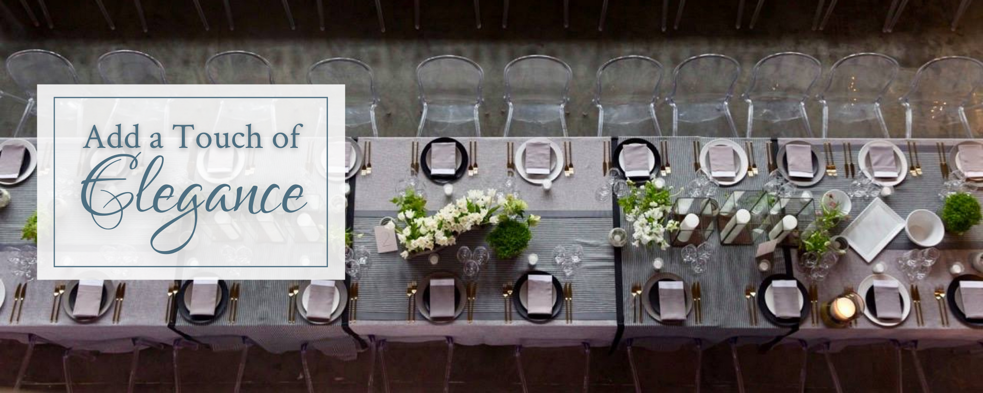 Table setting with white flowers, glassware, and a sign reading “Add a Touch of Elegance”