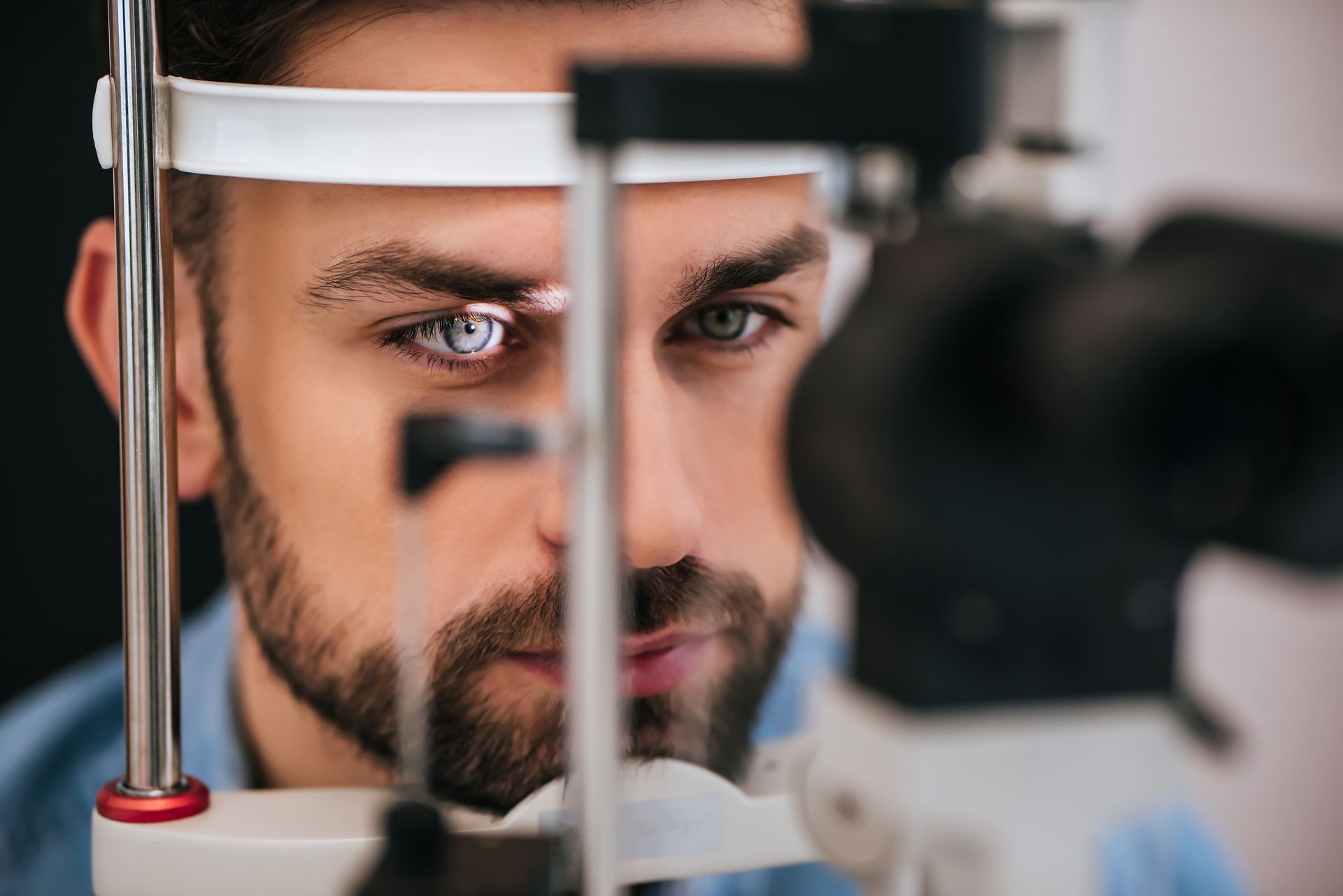 Scientist inspecting a microscope in a lab, focused through eyepieces with a blurred instrument in foreground