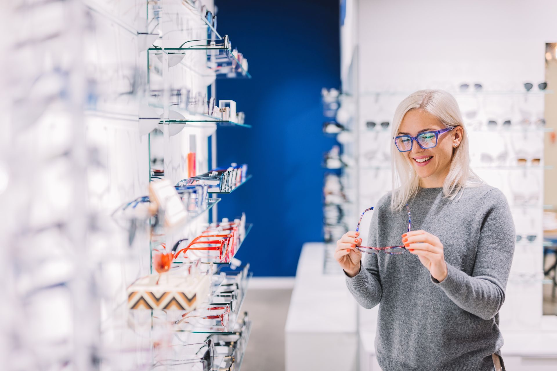 Woman adjusting eyeglasses in a bright optical store aisle with rows of eyeglass frames Woman adjusting eyeglasses in a bright optical store aisle with rows of eyeglass frames