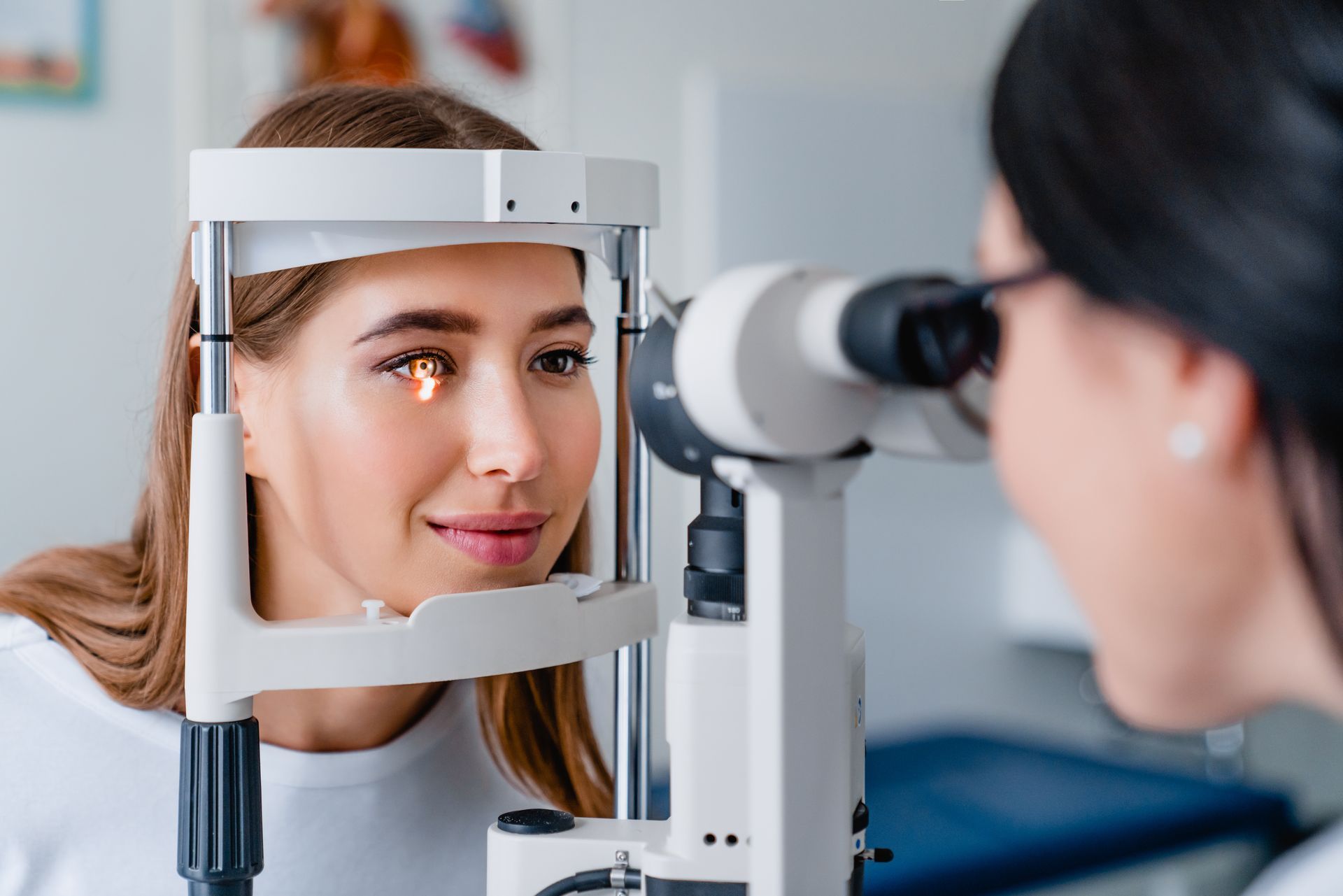 Patient at an eye exam looking into a phoropter while an optometrist examines her vision