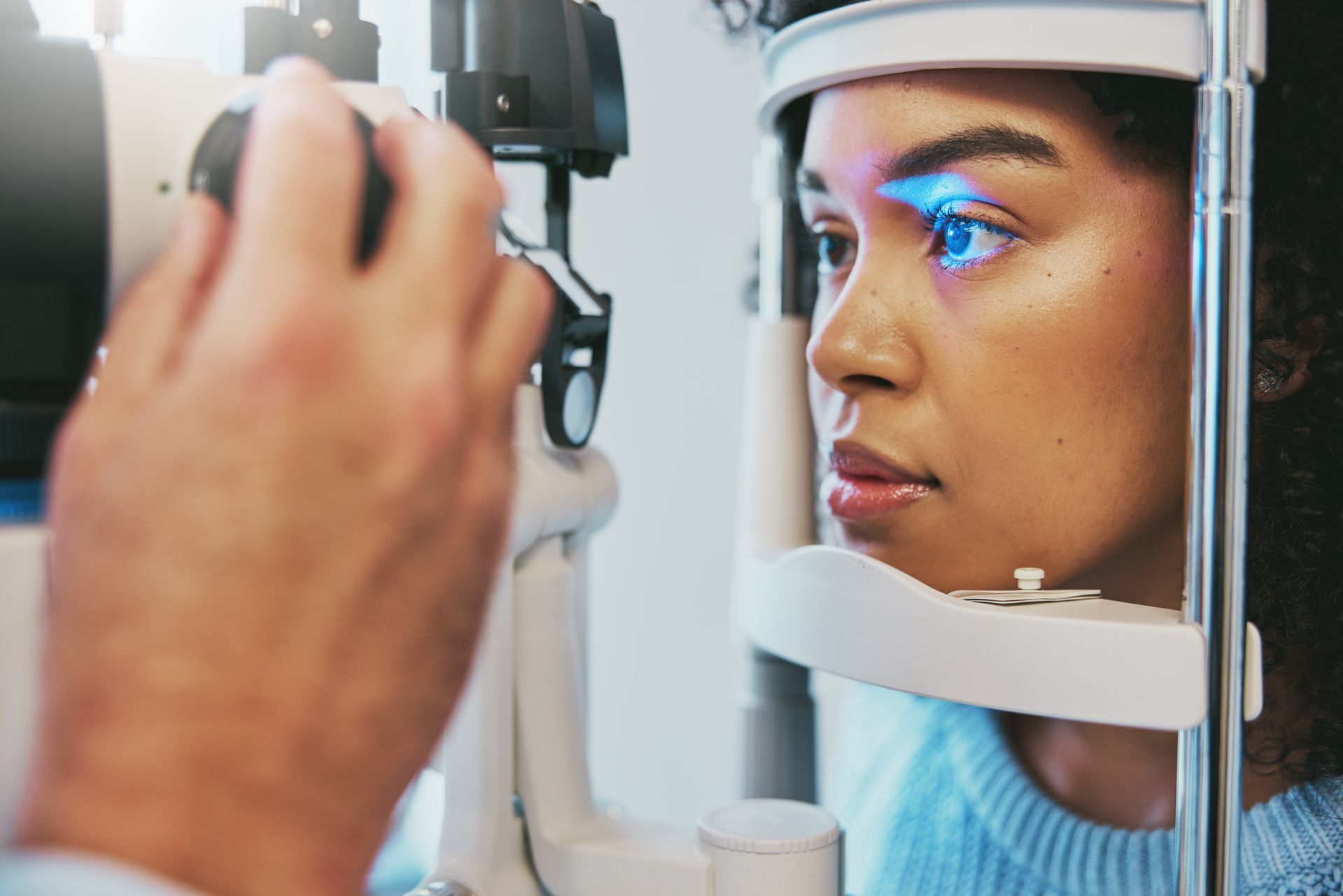 Eye exam in a clinic, with a patient looking through a phoropter as a doctor adjusts the machine.