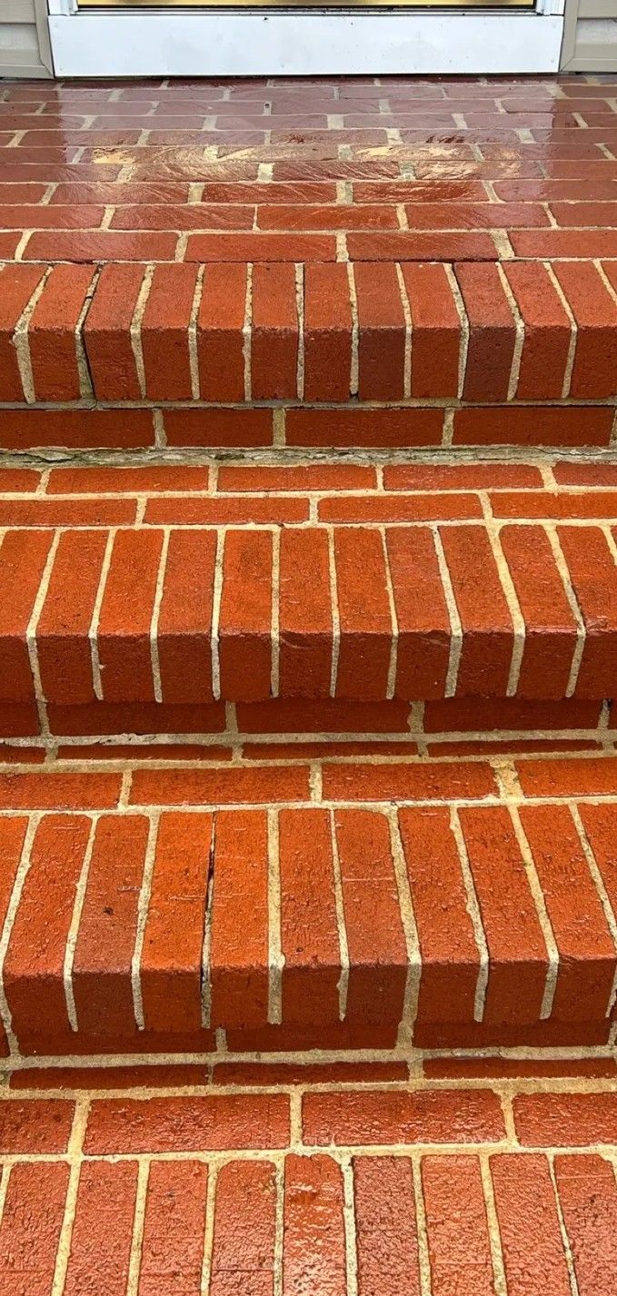 Brick steps with white anti-slip strips leading to a doorway