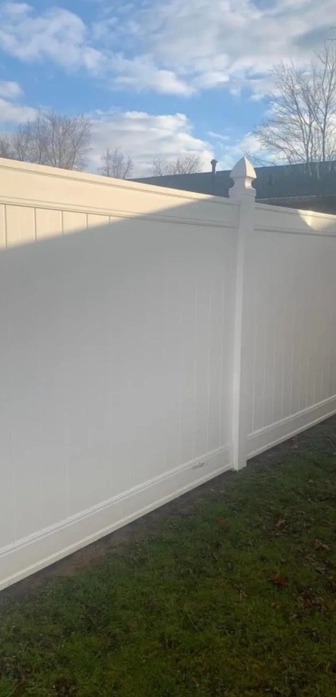 White vinyl fence beside a grassy yard under a partly cloudy sky