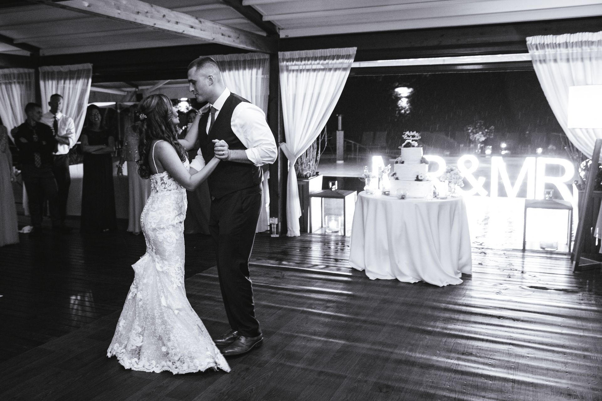 A couple in formal attire dancing in a dimly lit venue with a glowing 