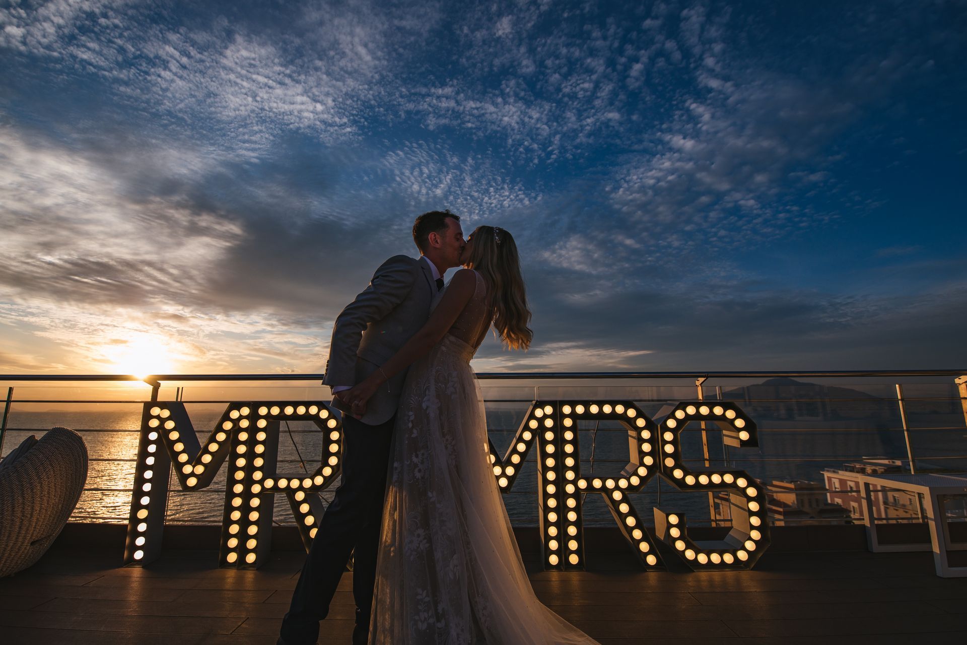 A couple kisses in front of lit 