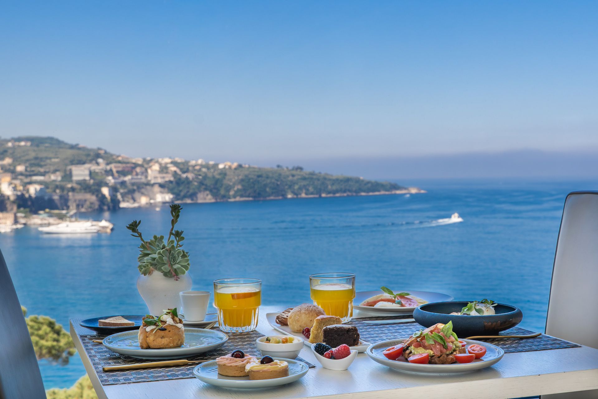 Colazione al Vesuvio Restaurant sul mare con pasticcini, succo d'arancia, caffè e vista sulla baia costiera.