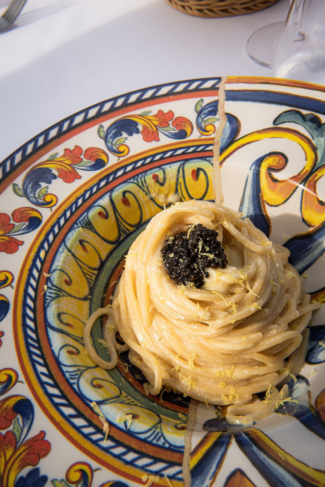 Una porzione singola di pasta condita con caviale, servita su un piatto decorativo colorato e decorato.