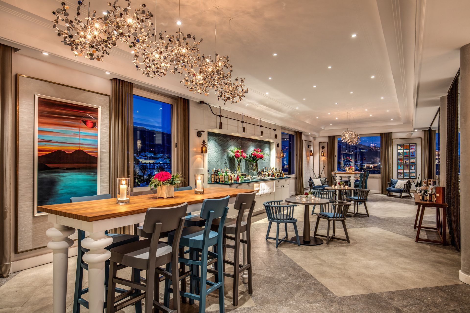 Elegante salone d'albergo con lampadari, sgabelli da bar e tavolini in un interno moderno e luminoso.