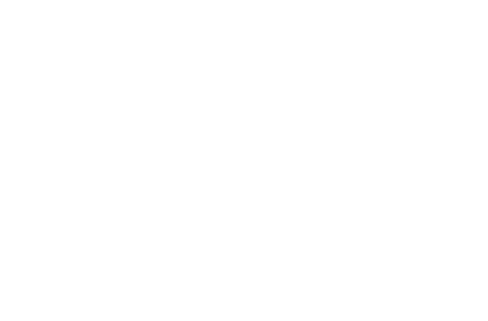 A person sitting on a chair reading a book, with shelves full of books in the background.