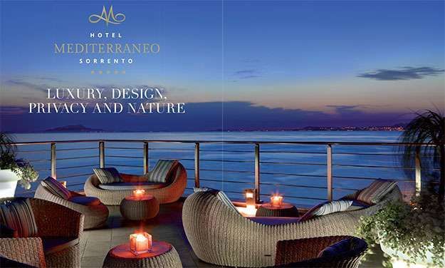 Lounge chairs on a terrace overlooking the sea at sunset, featuring the Hotel Mediterraneo Sorrento logo and branding.