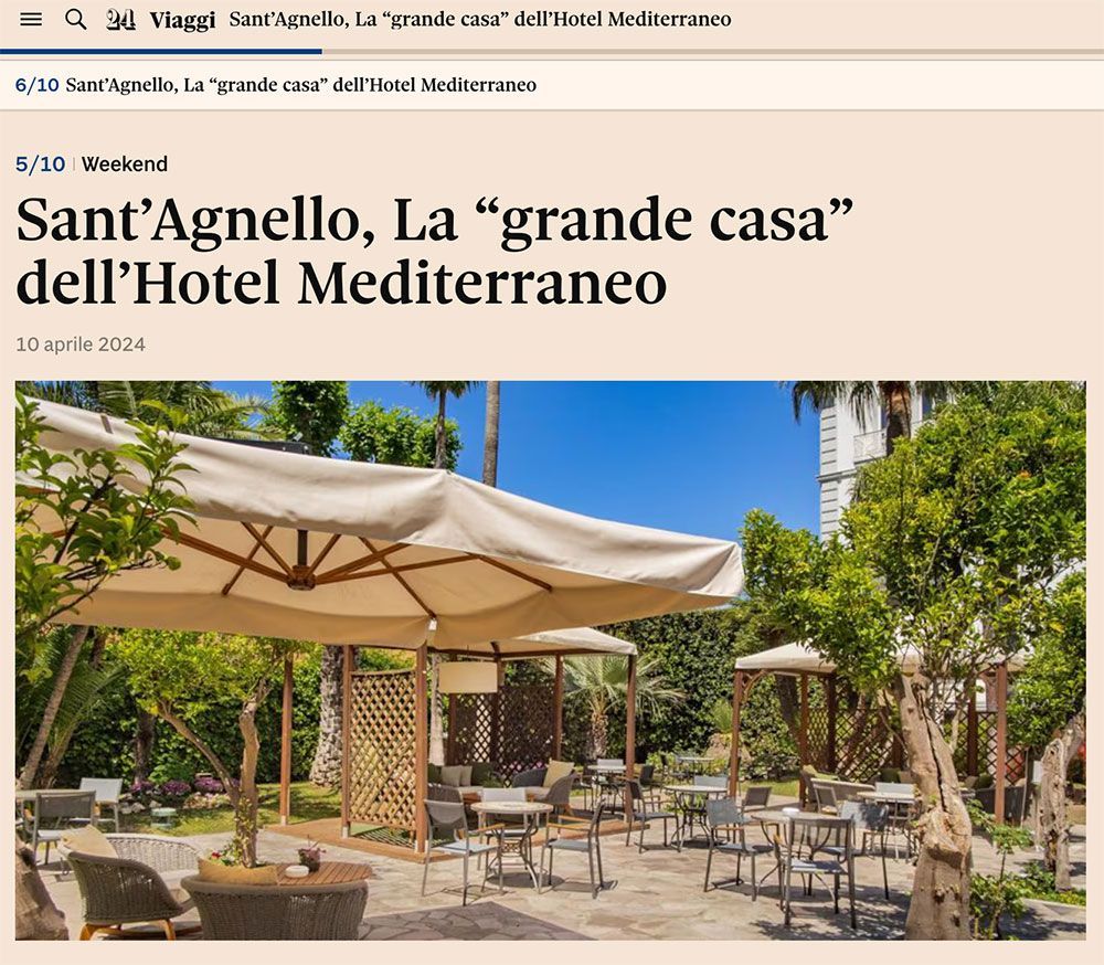 A sun-drenched outdoor hotel patio with tables, chairs, and large umbrellas in a lush, green garden setting.