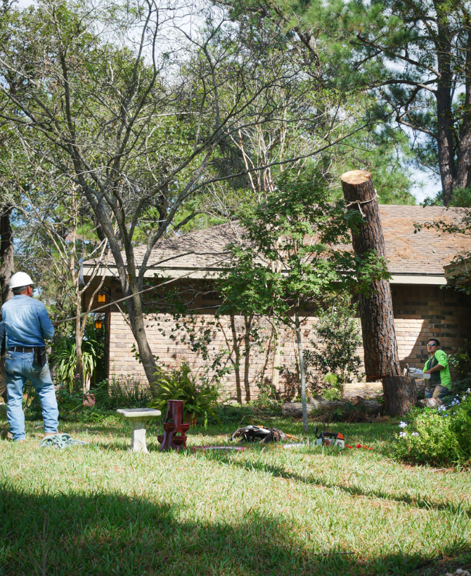 A man in a hard hat is standing in the grass in front of a house.