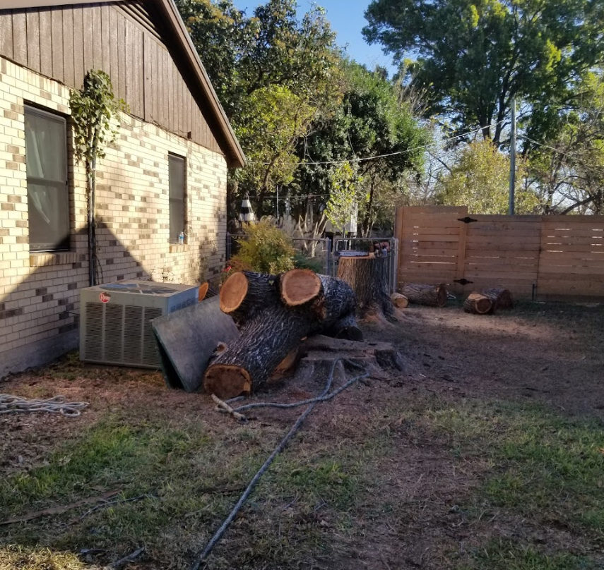 A pile of logs in front of a brick house