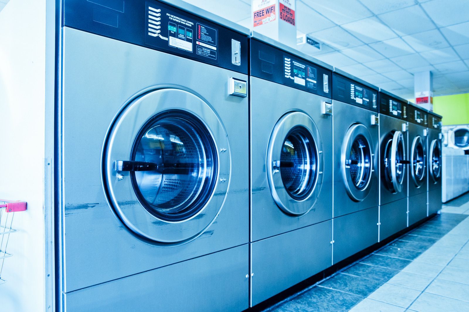 A row of washing machines are lined up in a laundromat.