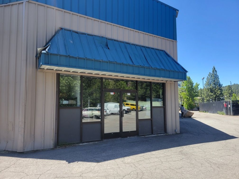 A building with a blue awning over the door and windows.