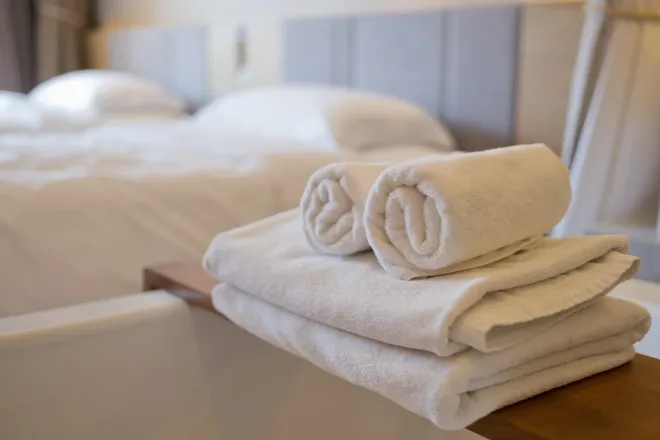 A stack of towels sitting on top of a bathtub in a hotel room.