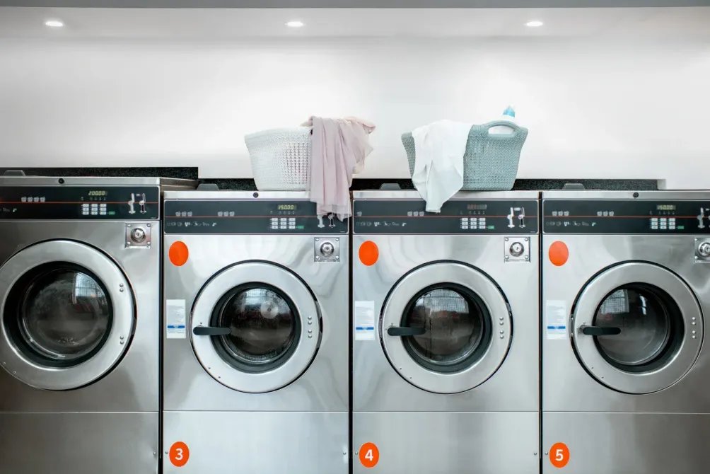 A row of washing machines are lined up in a laundromat.