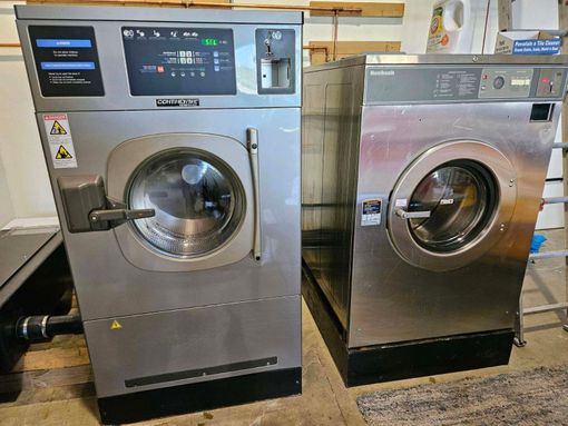 Two washing machines are sitting next to each other in a laundromat.