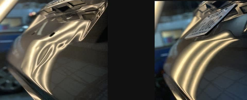 A car door with several noticeable dents. The metallic surface reflects light, highlighting the damage.